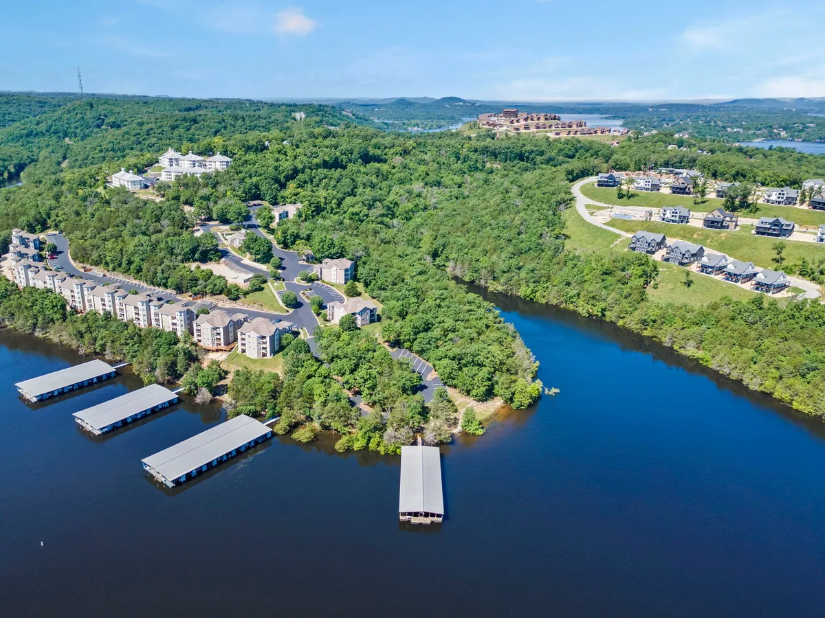 A serene lakeside scene featuring lakefront docks, calm water, and residential buildings framed by winding roads and wooded greenery. The area is ideal for boating, fishing, and lakeside relaxation, perfectly matching the resort’s direct access to Table Rock Lake.
