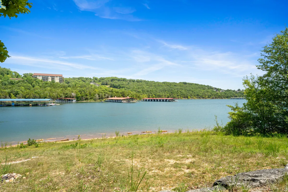 A sweeping view of Table Rock Lake framed by lush vegetation, serene docks, and an expansive sky. The calm water invites activities like boating and fishing, while the natural shoreline hints at hiking trails and lakeside picnics.