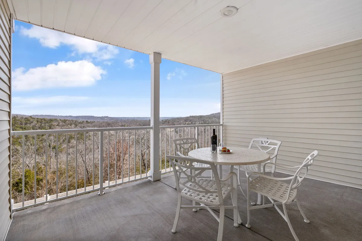 An outdoor table and chairs set on a private deck, complete with a bottle of wine, snacks, and a sweeping view of the landscape beyond. The scene is tranquil, inviting guests to relax or socialize outside.