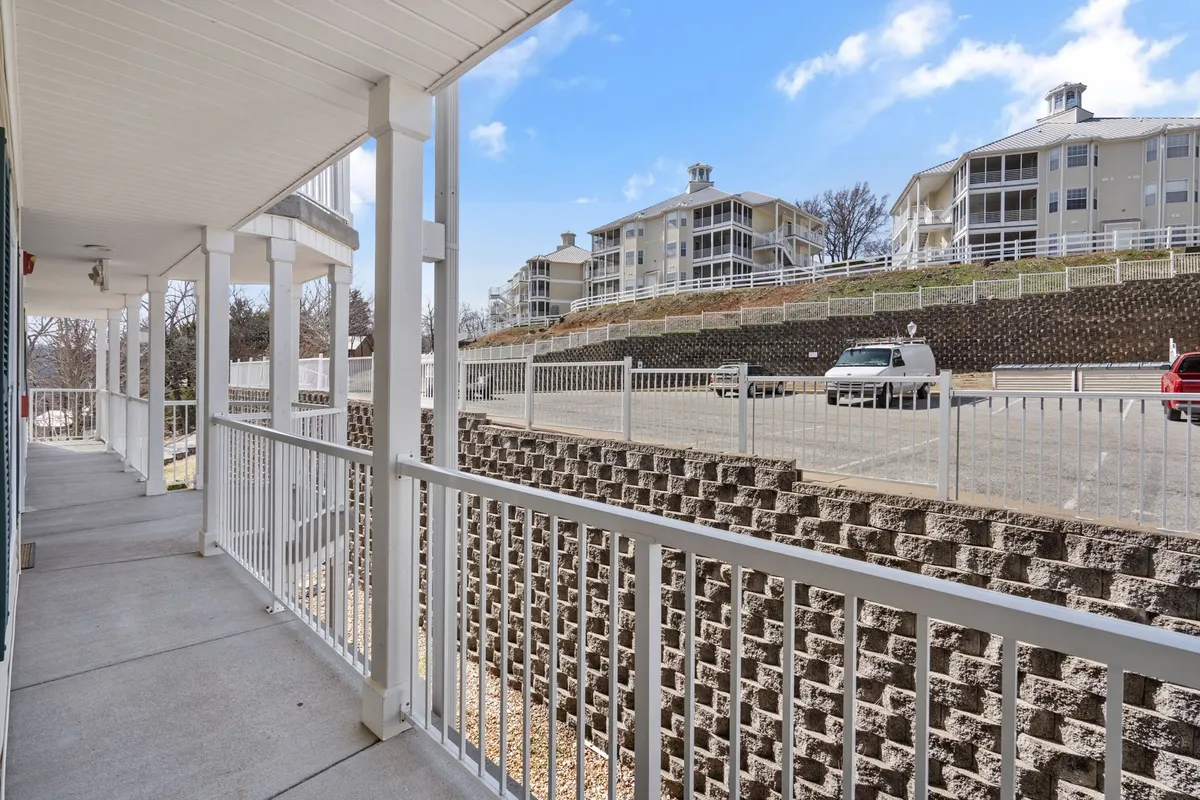 The photo shows a welcoming balcony overlooking a parking area and surrounding buildings, evoking the sense of a peaceful resort environment. The vantage point hints at easy indoor-outdoor transitions and opportunities to enjoy fresh air and sunshine.