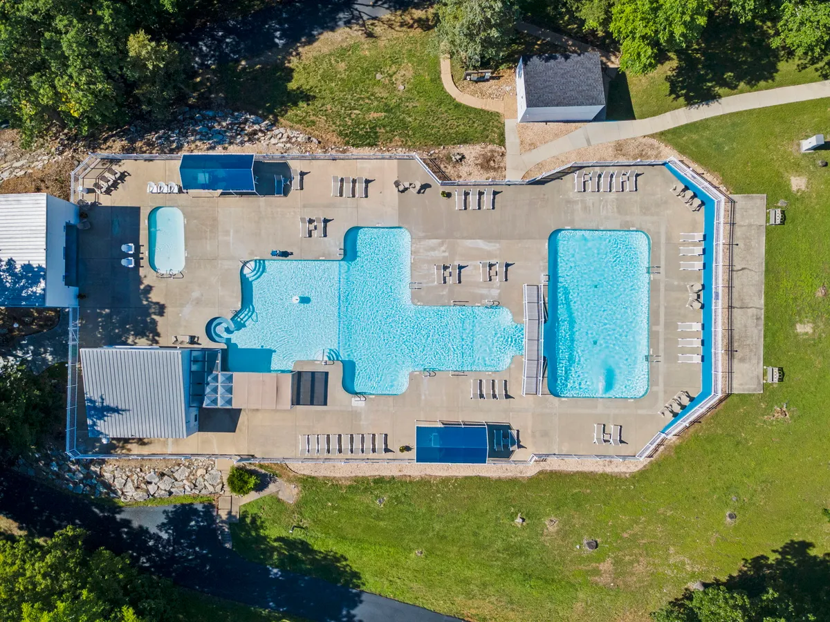 A large, inviting swimming pool with an adjacent smaller pool, surrounded by lounge chairs and lush greenery. The scene captures a leisurely, social mood with opportunities for swimming, sunbathing, or relaxing with friends and family.
