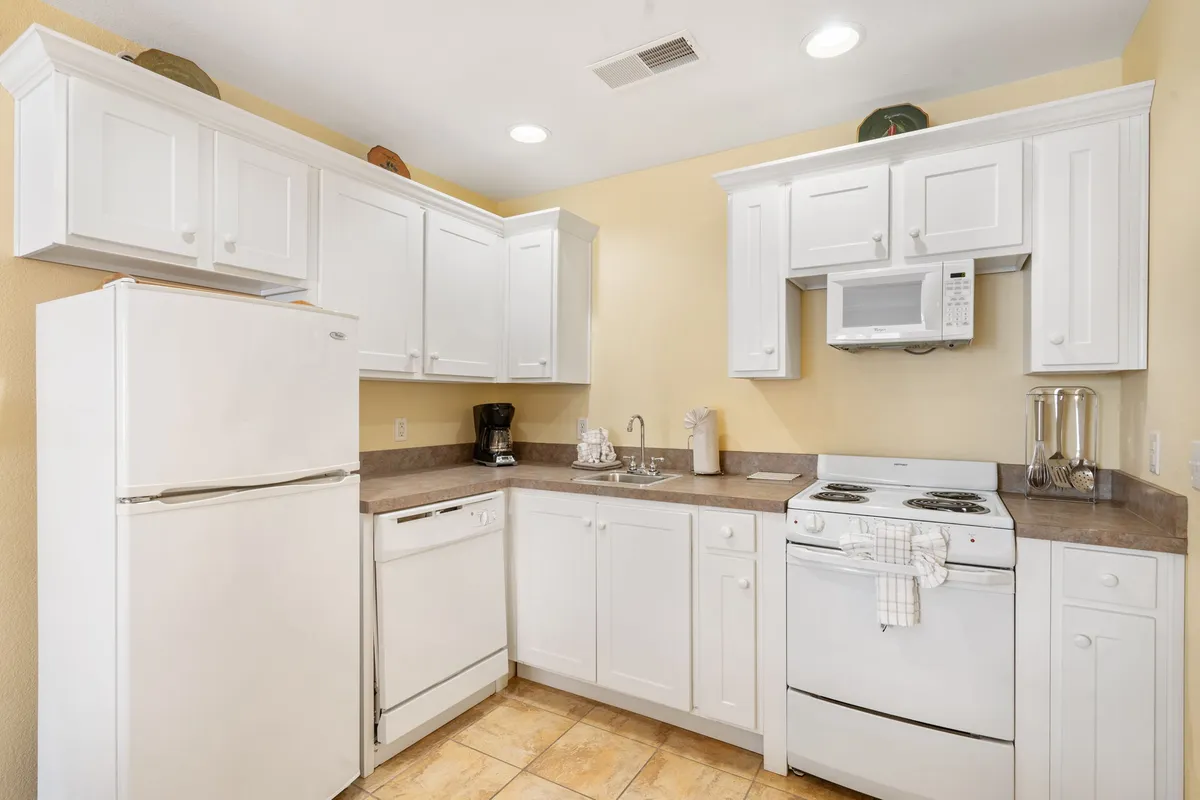 A modern kitchen with white cabinetry, stainless steel appliances, and a spacious countertop. The arrangement hints at both everyday meal prep and more elaborate cooking or entertaining, with an open flow into adjoining spaces.